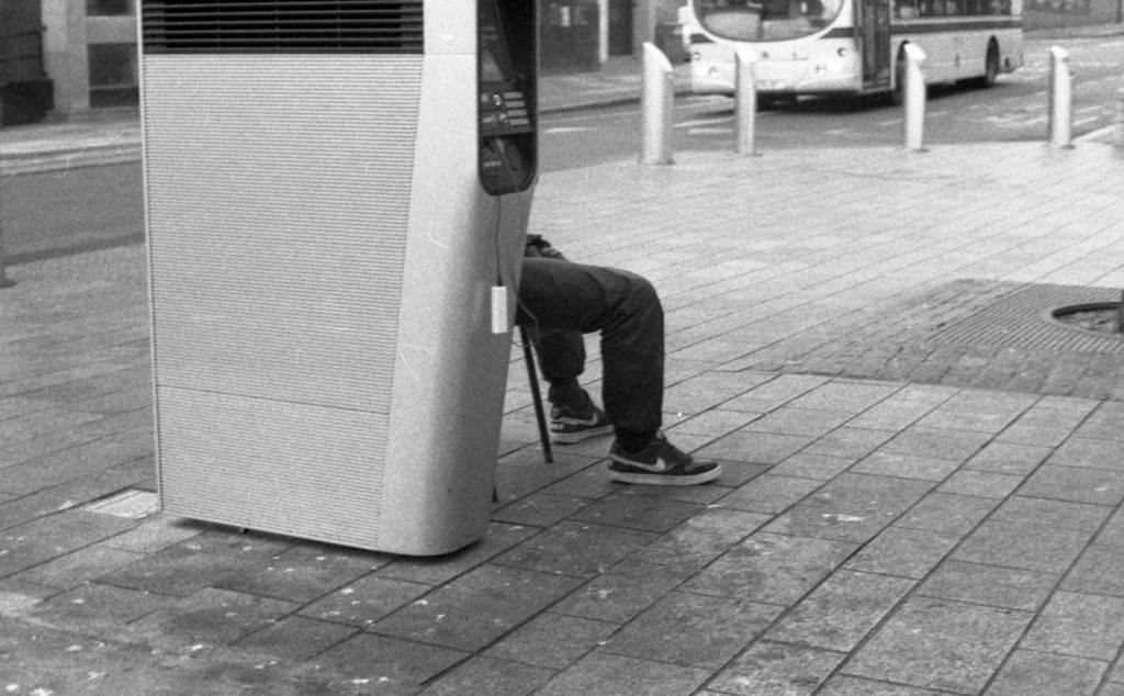A man charging his phone at a BT InLink hub in Sheffield
