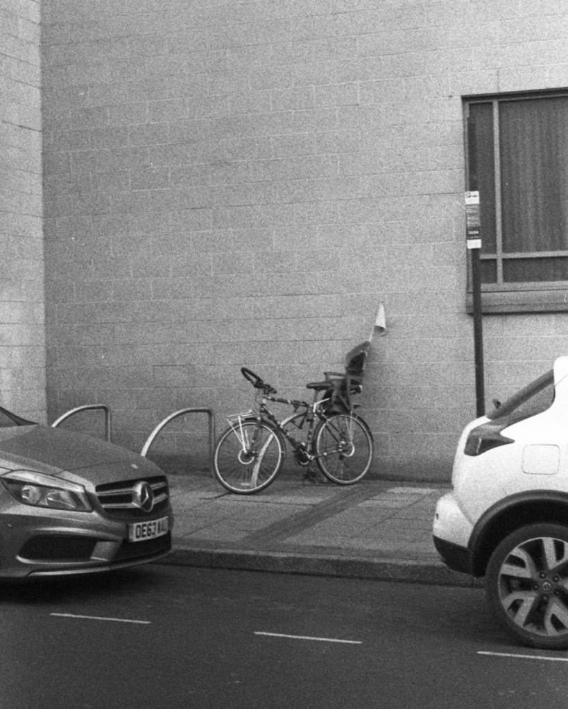 Bicycle with child seat and flag parked between two cars