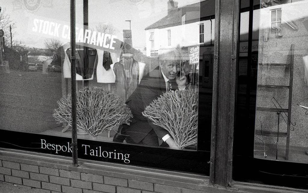 Man decorates window of tailored suit shop on London road Sheffield 