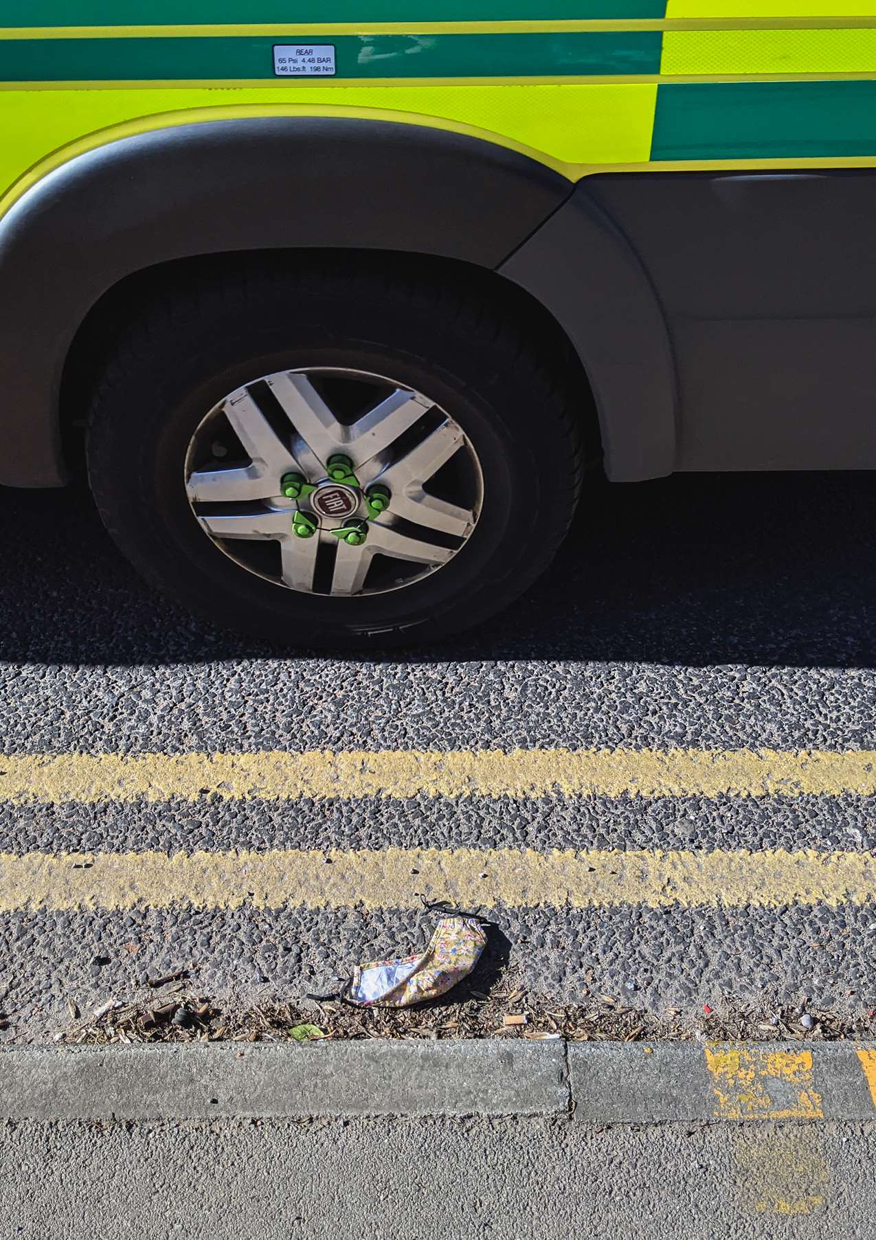 an abulance drives past a discarded yellow homemade mask